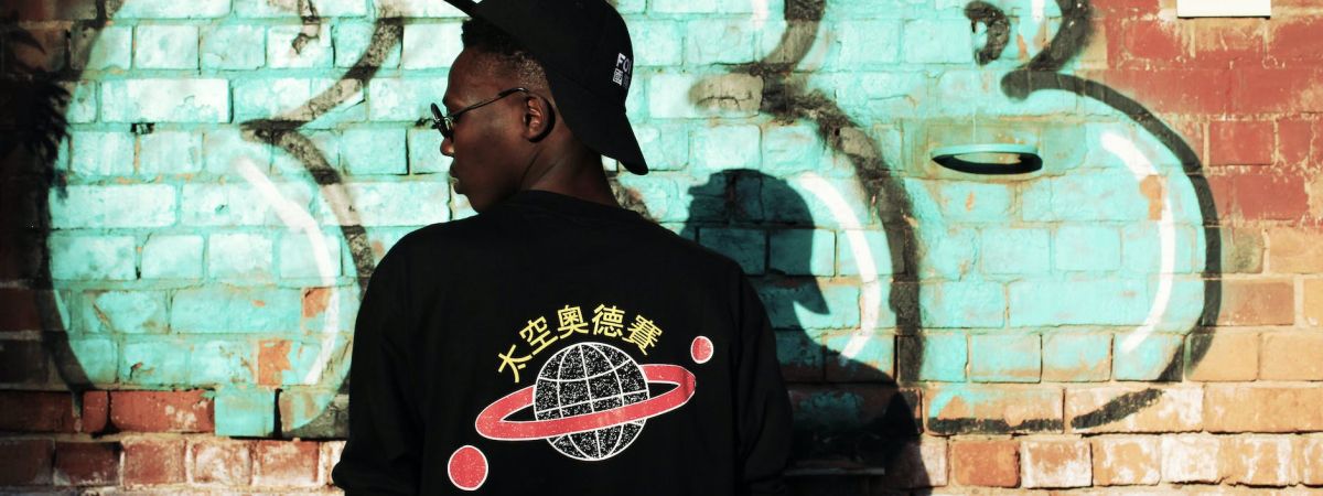 man wearing black long sleeved shirt stands near red wall