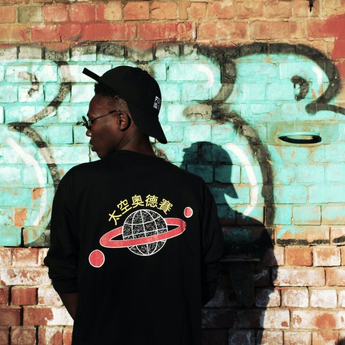 man wearing black long sleeved shirt stands near red wall